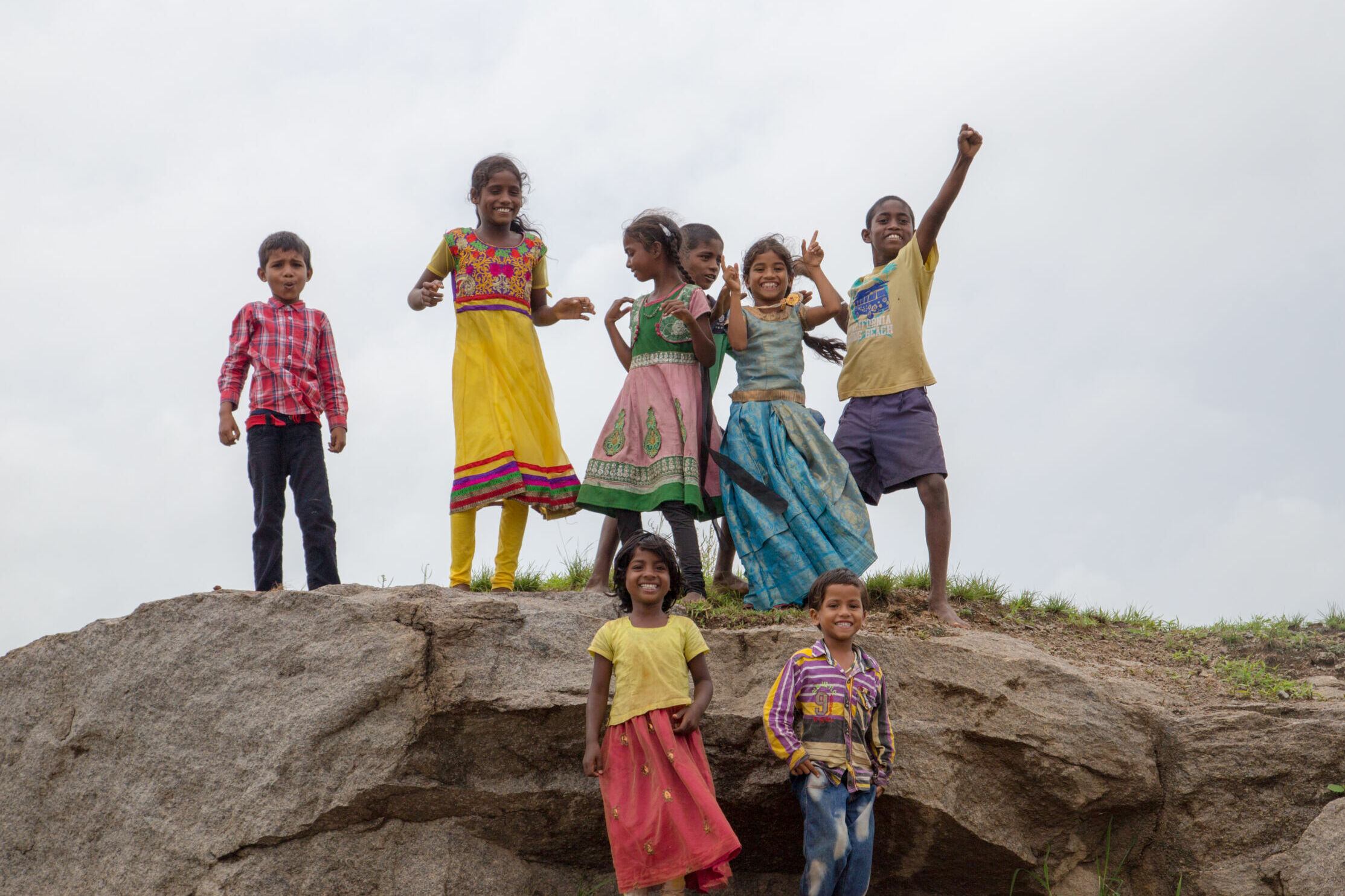a group of children standing on top of a hill smile widely at the camera
